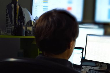 Hacker monitörün arkasında oturur ve çalışır. Bilgisayar teknisyeni ve programcının işi..