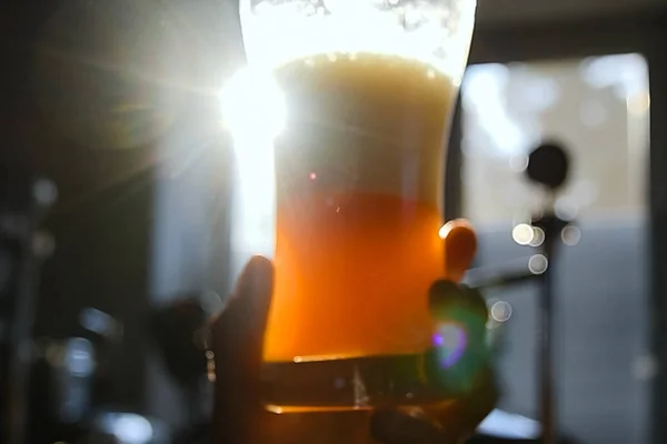 Glass of beer in the hand. Rotation of beer in a glass. Glass of beer against the backdrop of the sun.