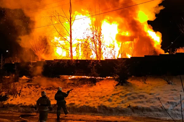 A house is burning, a house fire in a village, firefighters extinguish a house.