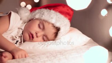 Çocuk Noel babalar şapka ve bekleyen Santas Hediyelik ile uyuyor. Altın ışık bokeh