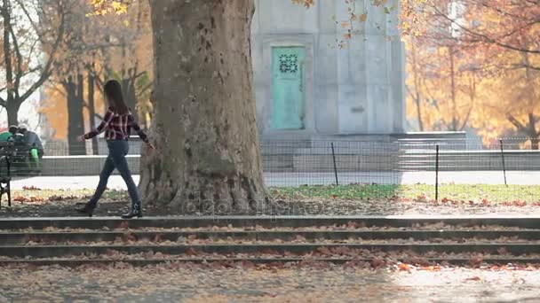 Счастливая женщина в осеннем парке. Радостная и взволнованная молодая женщина с удовольствием бросает желтые листья в солнечный осенний парк . — стоковое видео