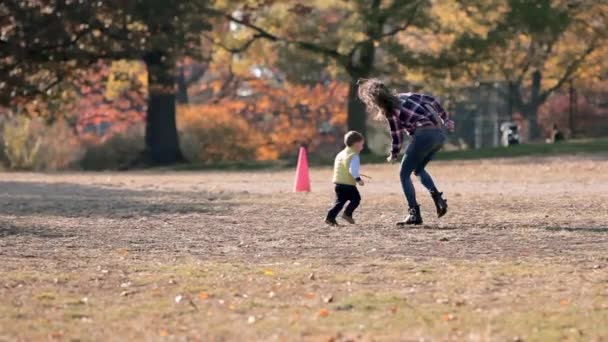 Young mother having fun with her kid son in autumn park, playing with leaves and birds — Stock Video