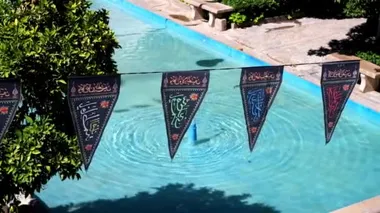 Şii Aşure Festivali bayraklarıyla Farsça dini yazıtlar çeşme arka planda, Şiraz, Iran ile Saraye Moshir çarşı Bahçe süslemeleri.