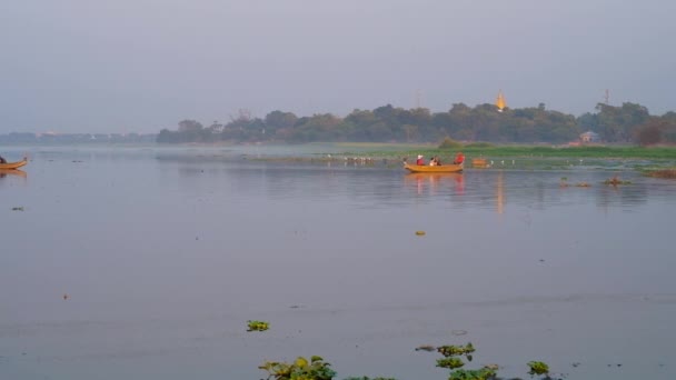 Taungthaman 湖の霧の夜アマラプラの緑の銀行に見られている背景には 夕日を眺め マンダレー ミャンマー Bein 橋へ伝統的な木製ボート — ストック動画