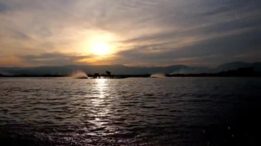 Arka planda güzel gün batımı ve Myanmar su yüzeyi parlak güneş yolu ile Kano tekneler Inle Gölü üzerinde yüzen hızlı.