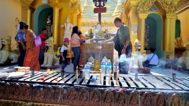 ヤンゴンで 前景にキャンドルを燃焼とヤンゴン ミャンマー 2018 仏教信者がシュエダゴン パゴダの仏像に水を注ぐの儀式を実行します — ストック動画