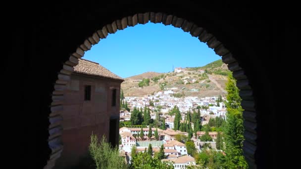 The carved Mudejar style arch of Alhambra opens the view on the fortress walls and Albaicin (Albayzin) neighborhood of hilly Granada Old Town, Andalusia, Spain 
