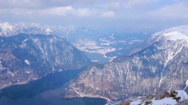 Krippenstein Dağı 'nın tepesinden Hallstattersee Gölü' nün kristal berrak yüzeyi Dachstein Alpleri, Salzkammergut, Avusturya 'nın karlı yamaçlarını yansıtır.