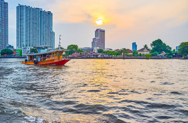 The old wooden boat sails along Chao Phraya river in dusk, Bangk