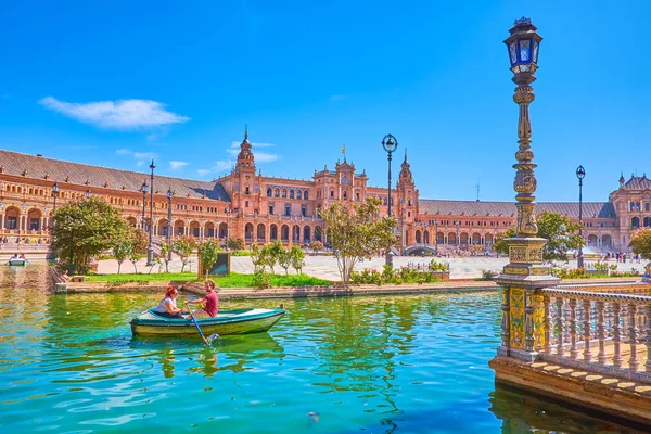 The couple sails along the canal in Plaza de Espana in Seville, — 스톡 사진