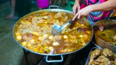 Kavrulmuş sığır sakatatı ve boğa testisi kaynayan büyük bir tavanın yakın çekimi, Talad Saphan Phut market, Dusit, Bangkok, Tayland