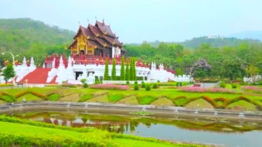 Etkileyici Kraliyet pyathat çatısı, yaldızlı desen, Singha aslanları ve Naga ejderhaları heykelleri, çiçek tarlaları, sulu çimenler ve dar kanallar, Rajapruek parkı, Chiang Mai, Tayland