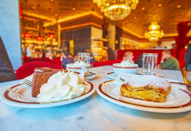 Viyana, Avusturya - 19 Şubat 2019: Lezzetli çikolatalı Sacher keki (Sachertorte) ve mükemmel Sacher Kafe 'de kremalı elmalı turta -popüler Wiener kahvesi, 19 Şubat' ta Viyana 'da