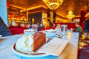 Viyana, Avusturya - 19 Şubat 2019: Geleneksel Viyana Sacher Kafe 'sini ziyaret edin ve 19 Şubat' ta Viyana 'da krem şantili lezzetli çikolatalı Sacher kekinin (Sachertorte) tadını çıkarın.