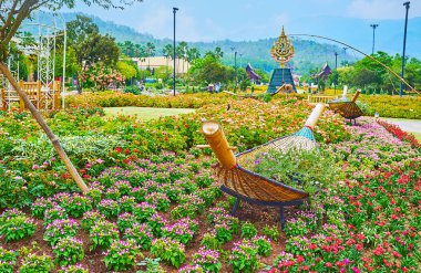 Chiang Mai, Tayland - 7 Mayıs 2019: Rajapruek parkının çiçek yataklarındaki hasır kano botları, arkaplanda Kraliyet Amblemi olan çeşme, 7 Mayıs 'ta Chiang Mai' de görüldü.