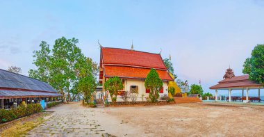 Panorama of Wat Phra That Mae Yen temple with ordination hall (ubosot) building, decorated with pyathat roof, Naga serpents and carved finials, Pai, Thailand clipart