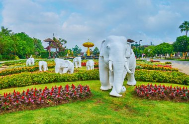 Chiang Mai, Tayland - 7 Mayıs 2019: Kraliyet Rajapruek Parkı 'nın çiçek tarlaları arasında koşan beyaz fillerin heykelleri, 7 Mayıs' ta Chiang Mai 'de, arka planda altın ağacı görmektedir.