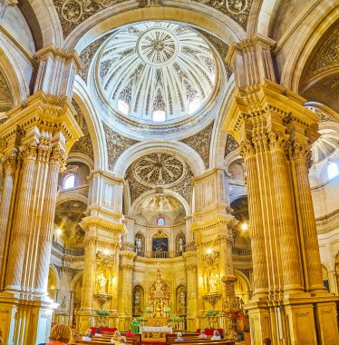 GRANADA, SPAIN - SEPTEMBER 27, 2019: Panoramic interior of Sagrario (Sacred Heart) church with huge columns, fine carved domes, sculptures of saints and ornate altarpiece, on September 27 in Granada