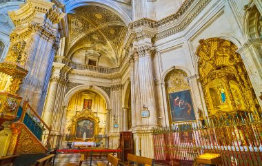 GRANADA, SPAIN - SEPTEMBER 27, 2019: The altarpieces of chapels in Sagrario (Sacred Heart) church decorated with beautiful paintings, carved gilt sculptures and frames, on September 27 in Granada