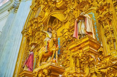 GRANADA, SPAIN - SEPTEMBER 25, 2019: The close-up details of Triunfo de Santiago Chapel in Granada Cathedral with ornate gilt plasterwork around the sculptures of saints and equestrian statue, on September 25 in Granada