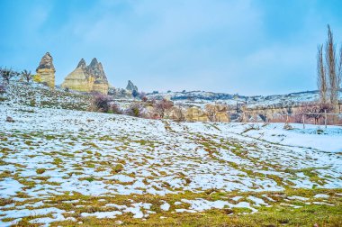 Goreme Vadisi 'ndeki karlı çimlerde peri bacası tuff kayaları, Kapadokya, Türkiye