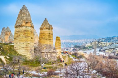 GOREME, TURKEY - JANUARY 17, 2015: The winter fog hovers around the tall yellow tuff rocks of fairy chimney formation, located in Goreme national park, Cappadocia, on January 17 in Goreme