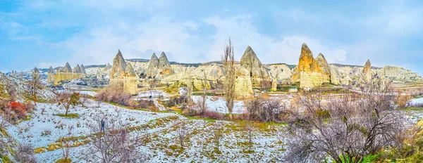Panorama of the unique landscape with weathered tuff rocks (fairy chimney formations) and snowy valley, Cappadocia, Goreme, Turkey