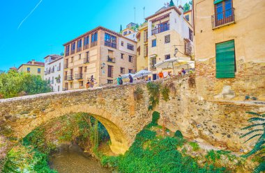 GRANADA, SPAIN - SEPTEMBER 25, 2019: Puente de Cabrera bridge over narrow Darro river is notable historic landmark, well seen from Carrera del Darro street, on September 25 in Granada