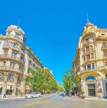 GRANADA, SPAIN - SEPTEMBER 25, 2019: Historical edifices with splendid corner facades face Calle Gran Via de Colon and Plaza Isabel la Catolica square, on September 25 in Granada