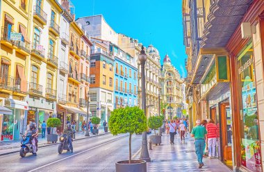 GRANADA, SPAIN - SEPTEMBER 25, 2019: The vibrant life in busy shopping Calle Reyes Catolicos street with luxury edifices, fast traffic, many fashion stores and cafes, on September 25 in Granada