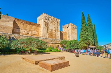 GRANADA, SPAIN - 25 Eylül 2019: Plaza de los Aljibes 'deki kuyruk büyük ortaçağ surlarının, Alhambra Kalesi' nin Kalesi ve Kırık Kulesi 'nin önünde 25 Eylül' de Granada 'da