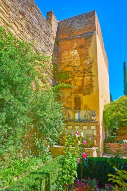 Adarves 'in yemyeşil bahçesi, Alcazaba, Alhambra, Granada, İspanya' nın duvarına iliştirilmiş eski Yunuslar çeşmesini gizler.