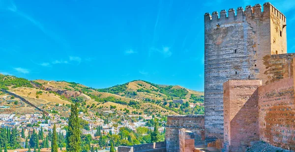 Panorama of Granada landscape with green hills, old town white housing and huge Keep (Torre del Homenaje) of Alcazaba fortress, Alhambra, Granada, Spain