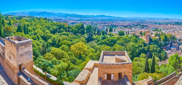 The Watch tower (Torre de la Vale) of Alcazaba overlooks the ramparts of Alhambra, the park on slope of Sabika hill, city districts and Sierra Nevada mountains, Granada, Spain