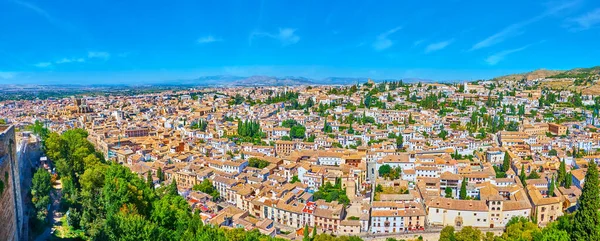 Alcazaba fortress is perfect viewpoint to enjoy the vista of old Granada, its small houses with tile roofs, medieval churches, green cypress trees and Sierra Nevada mountains on background, Spain