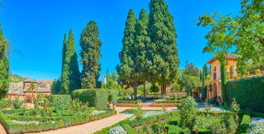 Granada, İspanya - 25 Eylül 2019 'da Granada' da Partal Bahçesi manzaralı çiçek yatakları, budanmış çalılar, palmiyeler ve uzun thuja ağaçları ile panorama