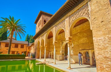 GRANADA, SPAIN - SEPTEMBER 25, 2019: The medieval portico of Partal palace of Alhambra with scenic sebka decors, slender stone pillars and pool in front of it, on September 25 in Granada clipart