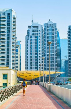 DUBAI, BAE - 2 Mart 2020: Dubai Marina üzerindeki Al Emreef Köprüsü, 2 Mart 'ta Dubai' deki metro istasyonunun Jumeirah Lake Kuleleri kompleksinin gökdelenleri ve fütürist pavyonu üzerine kurulmuştur.