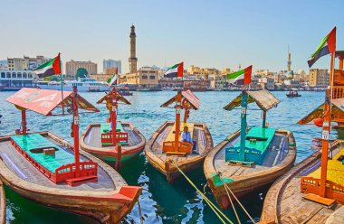 DUBAI, BAE - 2 Mart 2020: Eski ahşap abra tekneleri Deira ilçesindeki Dubai Deresi 'nin kıyısına demirli; 2 Mart' ta Dubai 'de Dubai' deki Büyük Cami ve Bur Dubai evlerinin minarkaplanda görülmektedir.