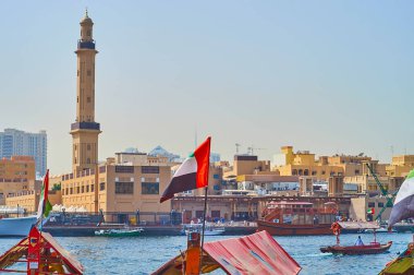 DUBAI, BAE - 2 Mart 2020: Dubai 'de yer alan ve Dubai deresi ve yüzen abra botlarının arkasında 2 Mart' ta Dubai 'de görülen Büyük Cami' nin uzun minaresi