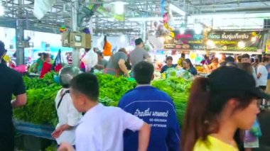 BANGKOK, THAILAND - 13 Mayıs 2019: 13 Mayıs 'ta Bangkok' ta Talad Saphan Phut pazarının üretim bölümünde bulunan bir yığın yeşillik ve otla dolu tezgahtaki müşteriler