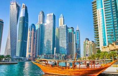 DUBAI, BAE - 2 Mart 2020: Dubai Marina 'da modern teknolojilerin ve geleneksel yaşam tarzının birleşimi - cam gökdelenler ormanının önündeki klasik ahşap dhow teknesi, 2 Mart' ta Dubai 'de