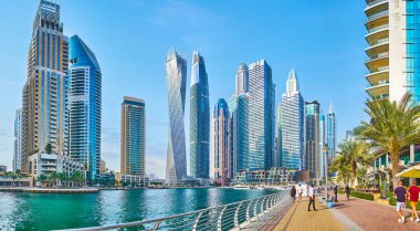 DUBAI, BAE - 2 Mart 2020: Dubai Marina 'nın cam ve beton gökdelenler hattı boyunca yürüyüp, 2 Mart' ta Dubai 'de berrak suların arkasında görüldü.