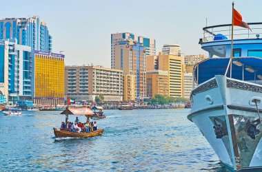 DUBAI, BAE - 2 Mart 2020: Abra teknesi Dubai deresi boyunca 2 Mart 'ta Dubai' de demirli gemi ve modern Deira kamaraları manzarası ile yüzüyor.