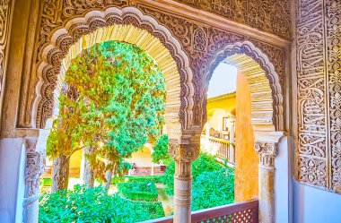 Granada, İspanya - 25 Eylül 2019: Aslanlar Sarayı 'ndaki (Nasrid Palace, Alhambra) karmaşık oymalı pencereler, 25 Eylül' de Granada 'daki yemyeşil Daraxa' nın Bahçesi 'nin manzarasını açar.