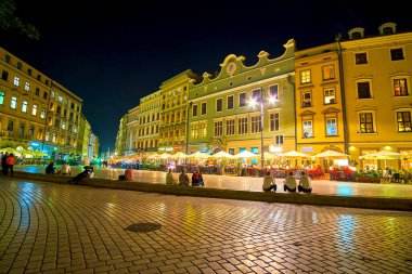 KRAKOW, POLAND - 12 Haziran 2018: Manzaralı gece aydınlatmasında zemin katta kafeleri olan tarihi evler dizisi, 12 Haziran 'da Krakow