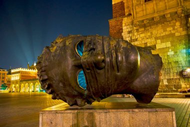 KRAKOW, POLAND - 12 Haziran 2018: Ana Pazar Sqaure ve modern heykel Eros Bendato 'daki binaların gece aydınlanması, 12 Haziran' da Krakow 'da
