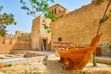 The old clay street with authentic housing is decorated with traditional fishing boat, Al Bastakiya (Al Fahidi), Dubai, UAE clipart
