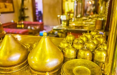 Kapaklı klasik pirinç renkli Arap kahve fincanlarının yakın çekimi, Dubai, BAE 'deki sokak kahve sepetinin panelinde.