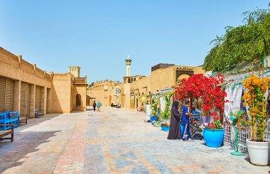 DUBAI, BAE - 2 Mart 2020 'de Al Bastakiya (Al Fahidi) mahallesindeki küçük meydanda kil evler ve rahat kafeler, çiçek açan bougainvillea çalıları ile süslenmiş, 2 Mart' ta Dubai 'de